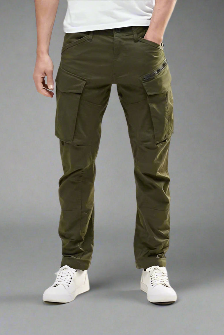 Person wearing olive green cargo pants on a gray background