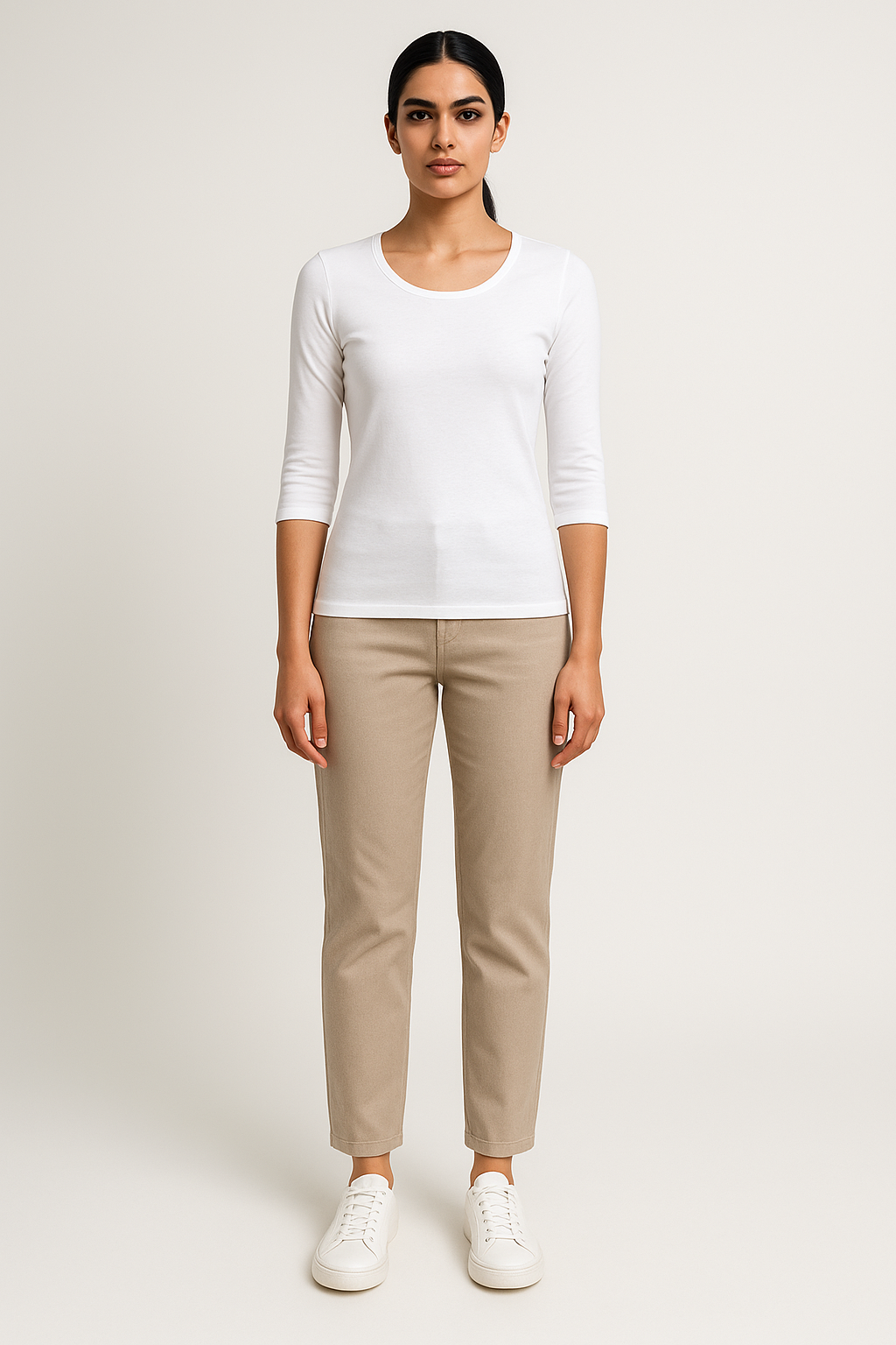 Woman wearing a white top and beige pants on a plain background