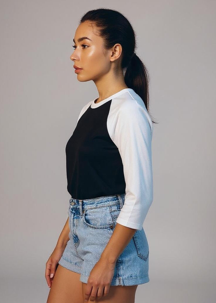 Woman wearing a black and white long-sleeve top with denim shorts on a gray background