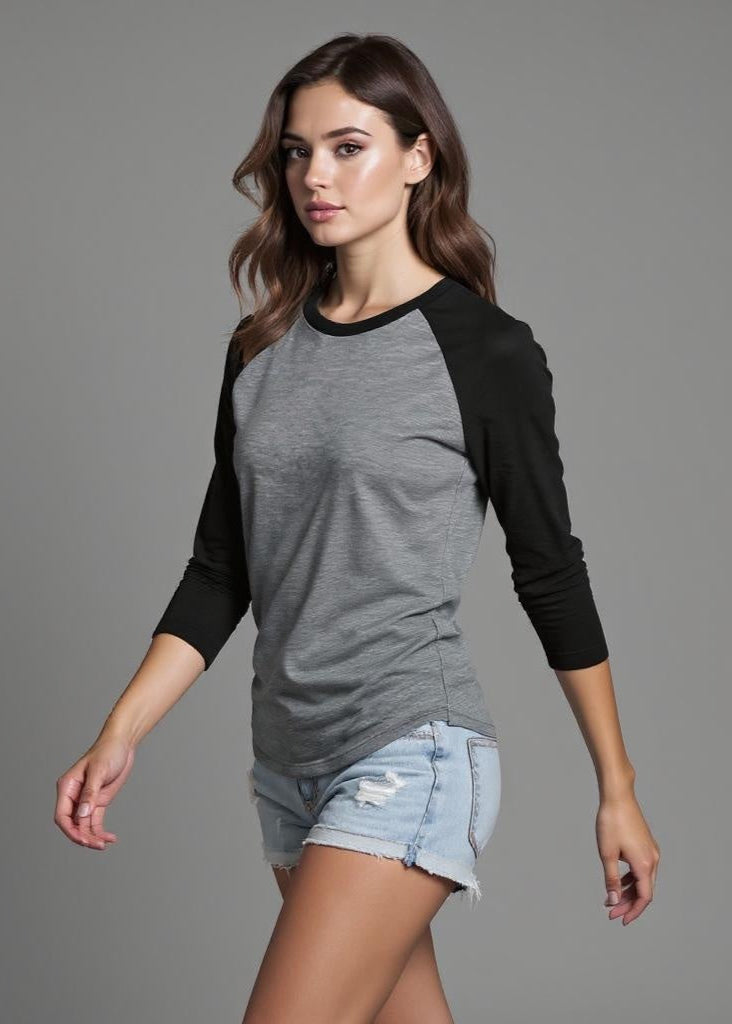 Woman wearing a gray and black long-sleeve shirt with denim shorts on a gray background