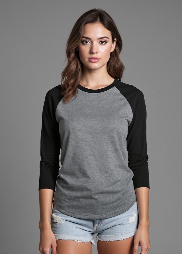 Woman wearing a gray and black long-sleeve shirt with denim shorts on a gray background