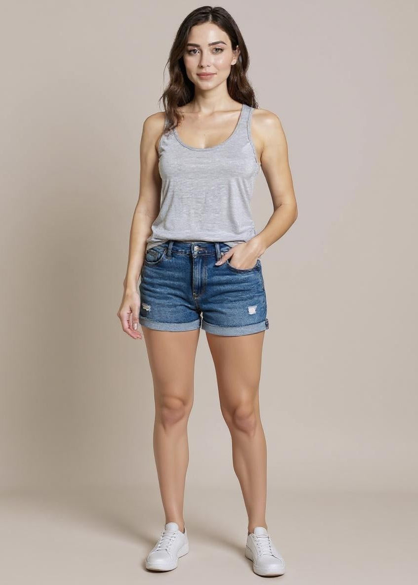 Woman wearing a gray tank top and blue denim shorts on a beige background