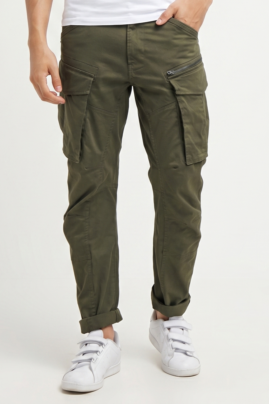 Person wearing olive green cargo pants on a white background
