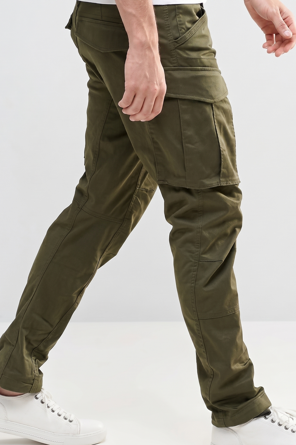 Person wearing olive green cargo pants on a white background