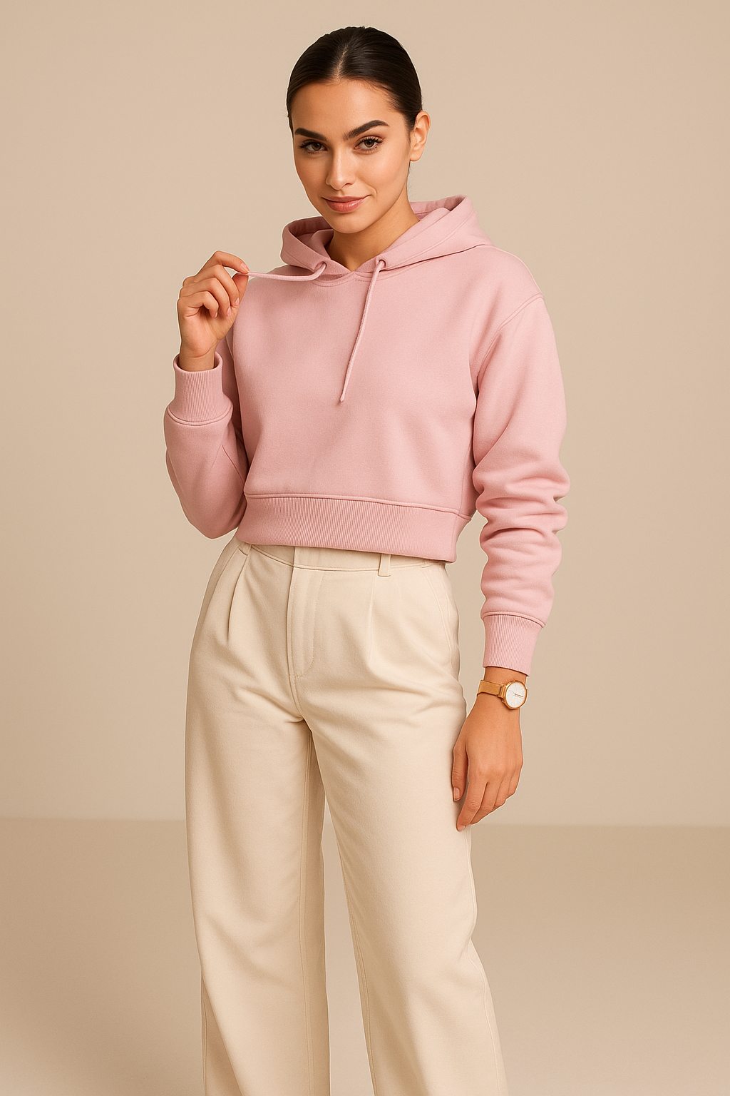 Woman wearing a pink hoodie and beige pants against a beige background