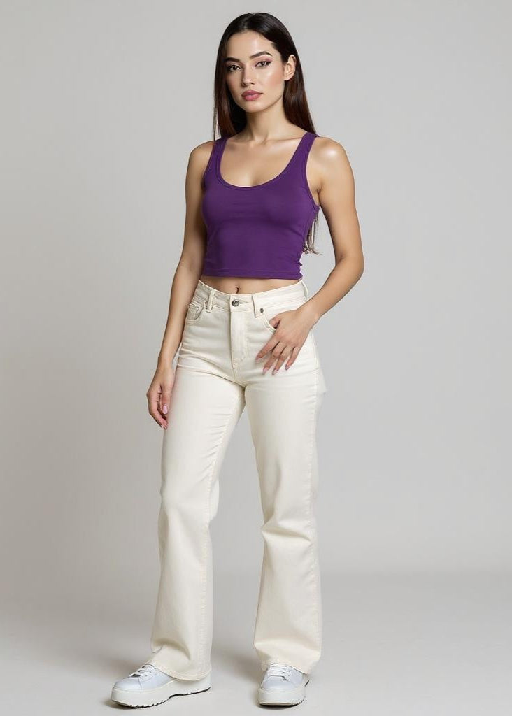 Woman wearing a purple tank top and white pants on a plain background