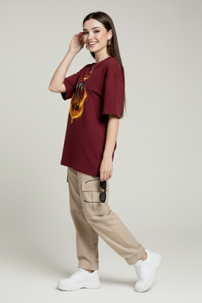 Woman wearing a burgundy t-shirt with a graphic design, beige cargo pants, and white sneakers on a plain background