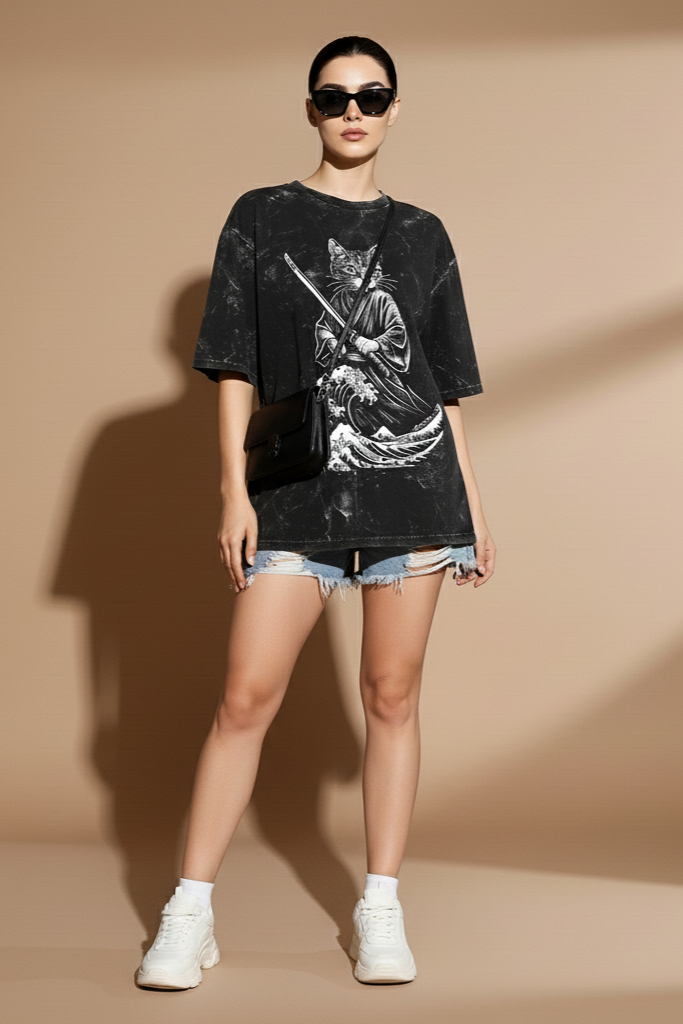 Woman wearing a black graphic t-shirt and denim shorts on a beige background