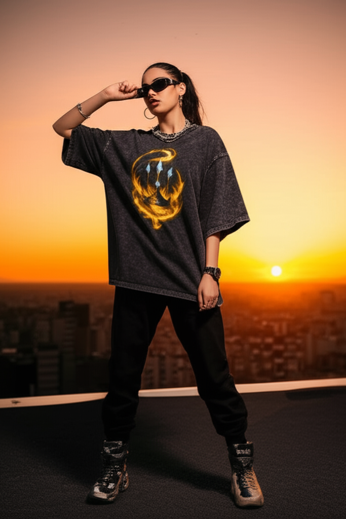 Person wearing a dark oversized shirt with a graphic design, standing against a sunset cityscape.