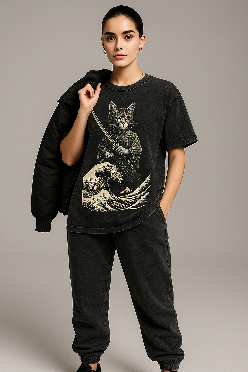 Person wearing a black t-shirt with a graphic design of a cat in a kimono holding a sword on a beige background